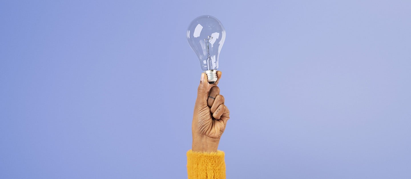 Raised hand holding a clear lightbulb